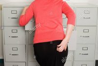 Rear View Of Businesswoman Looking In Filing Cabinet Stock Photo for measurements 866 X 1390