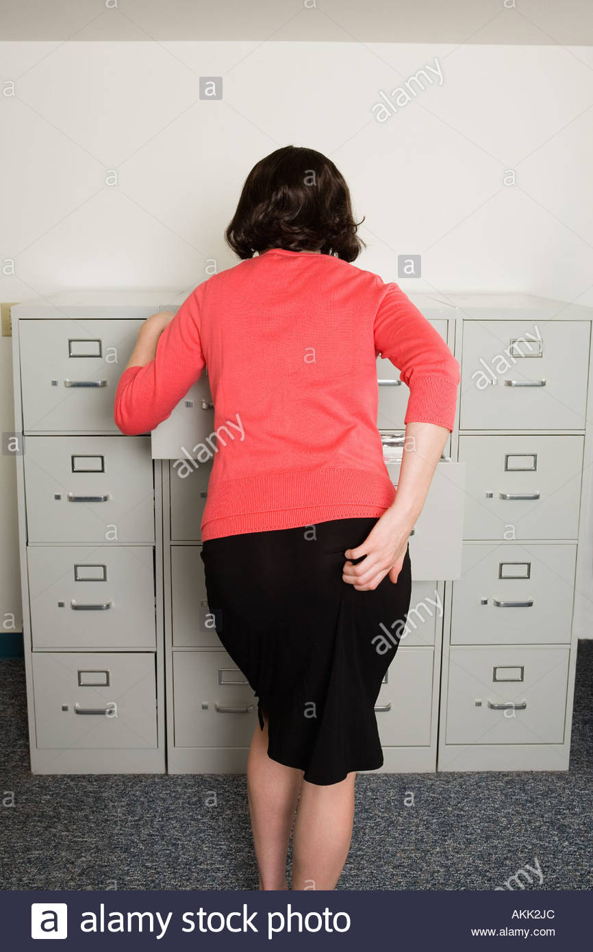 Rear View Of Businesswoman Looking In Filing Cabinet Stock Photo for measurements 866 X 1390